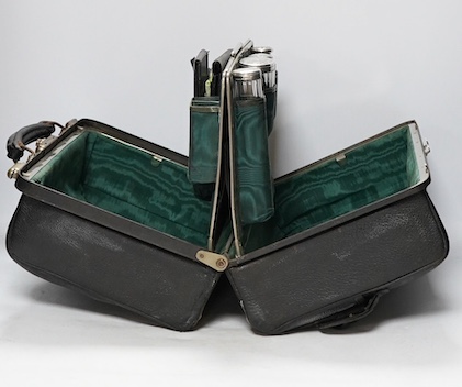 An Edwardian leather portmanteau case containing silver topped glass jars, the silver mm. TL, London 1904, case 36.5cm wide. Condition - fair